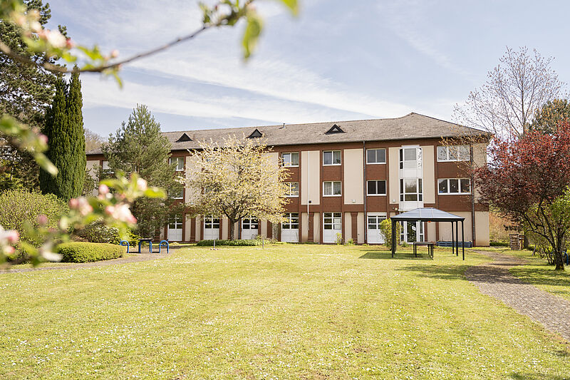 Ein Gebäude mit großem Garten mit gemähtem Rasen und Bäumen. 